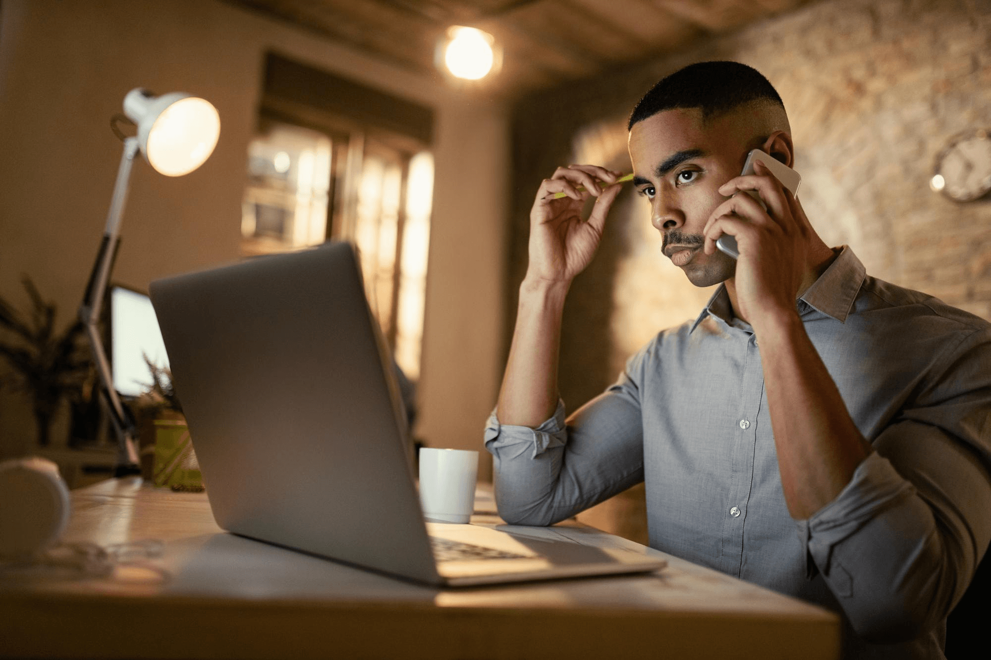 Empreendedor MEI usando notebook e telefone enquanto protege o endereço residencial