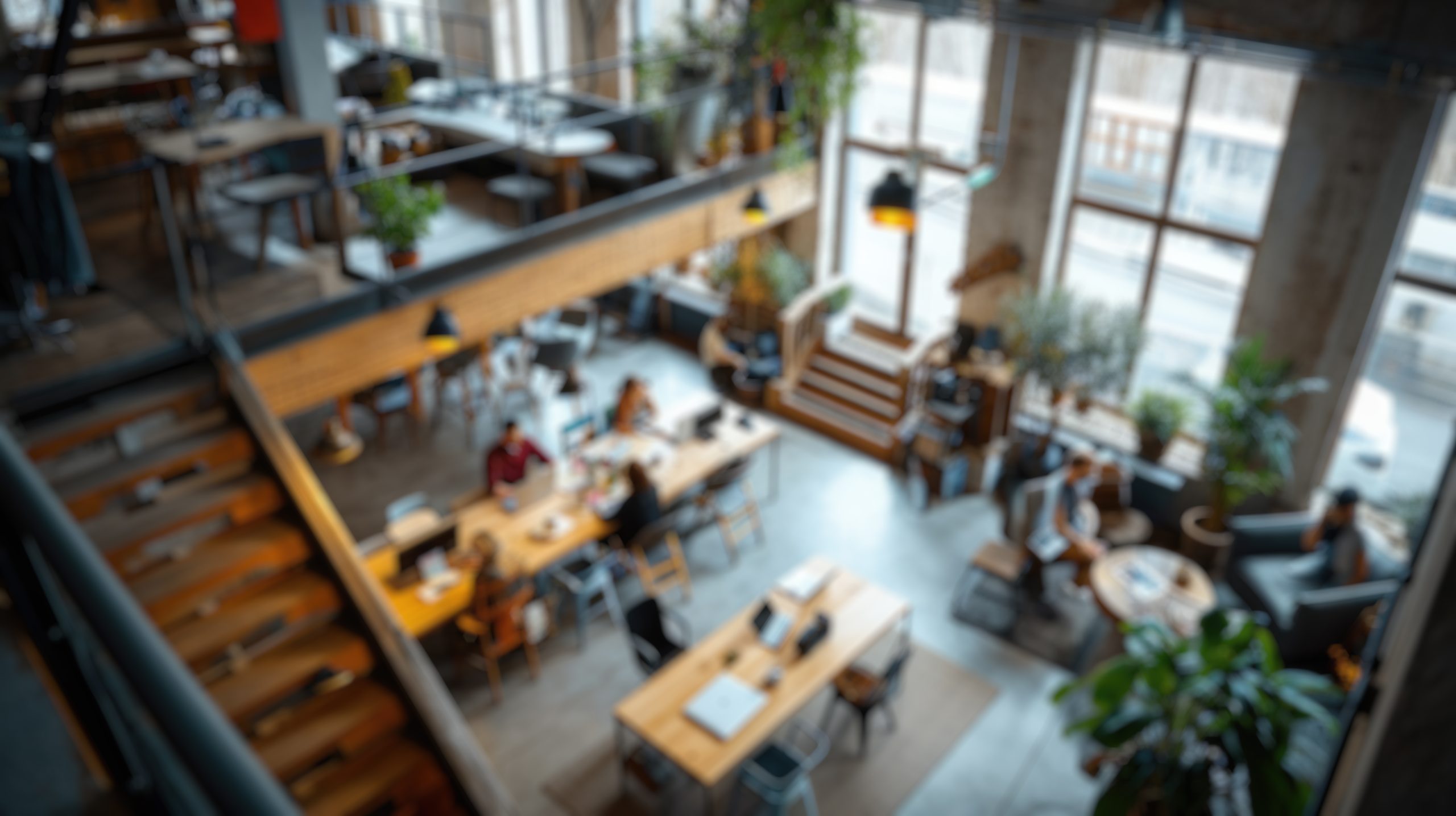 Defocused image of a lively modern coworking area with people and indoor plants. Resplendent.